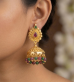 gold-plated traditional Indian jhumka earrings featuring ruby- red and emerald-green kemp stones with dangling bead accents.